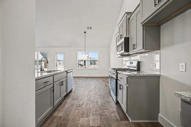 a kitchen with stainless steel appliances granite countertop lots of counter space and wooden floors