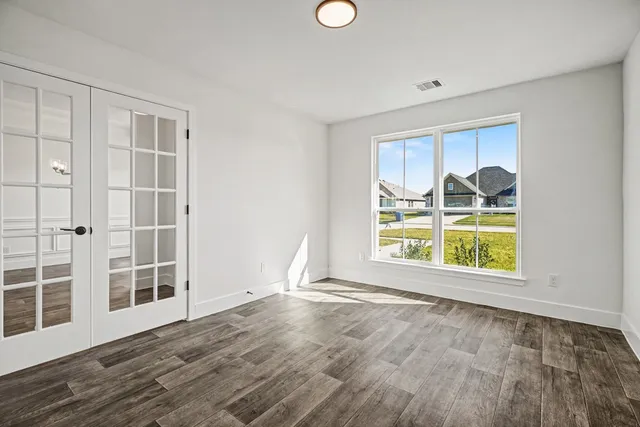 an empty room with wooden floor and windows