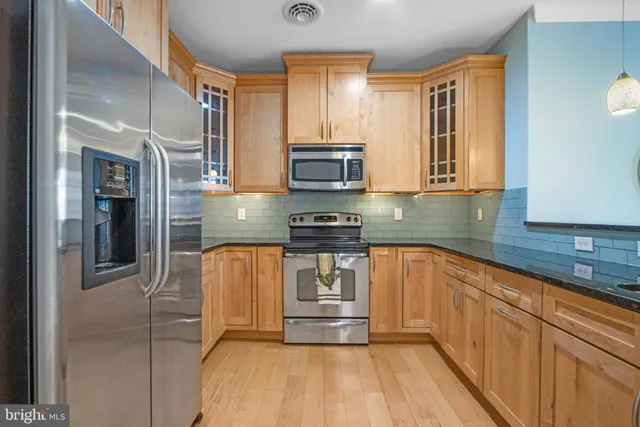 a kitchen with granite countertop wood cabinets and stainless steel appliances