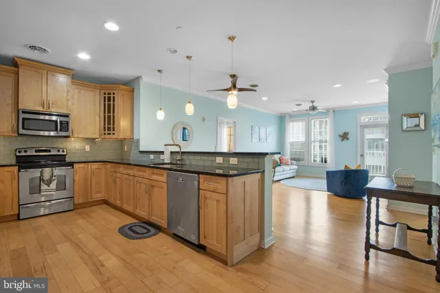 a kitchen with stainless steel appliances granite countertop a stove top oven a sink dishwasher a dining table and chairs with wooden floor