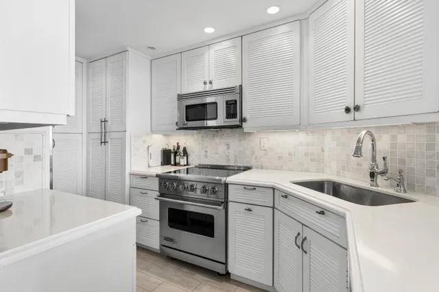 a kitchen with white cabinets sink and stainless steel appliances