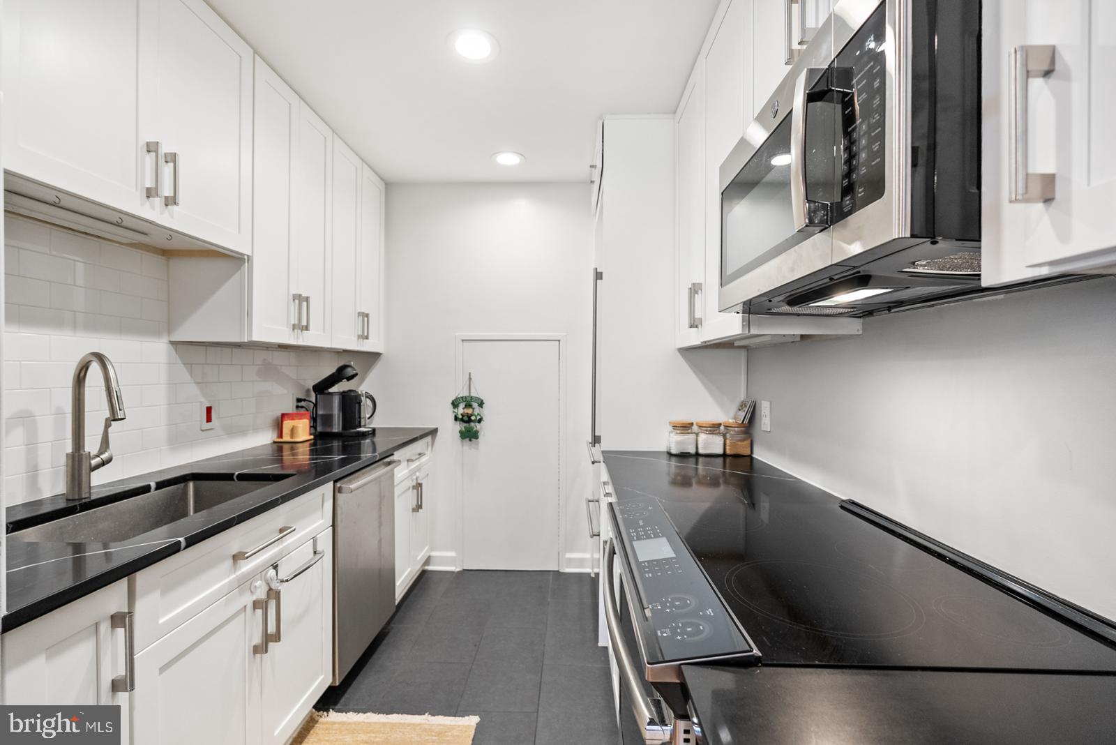 1710 Summit Place Northwest, Unit 1710 Washington, DC 20009 - Photo 2 of 35 a kitchen with stainless steel appliances granite countertop a sink a stove and a microwave oven with cabinets