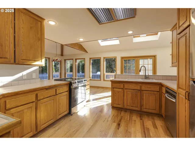 a kitchen with stainless steel appliances granite countertop a refrigerator a sink dishwasher and wooden cabinets with wooden floor