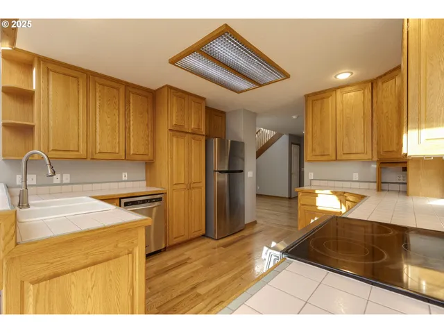a kitchen with stainless steel appliances granite countertop a sink refrigerator and cabinets