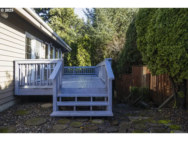 a view of wooden house with a yard balcony and wooden fence