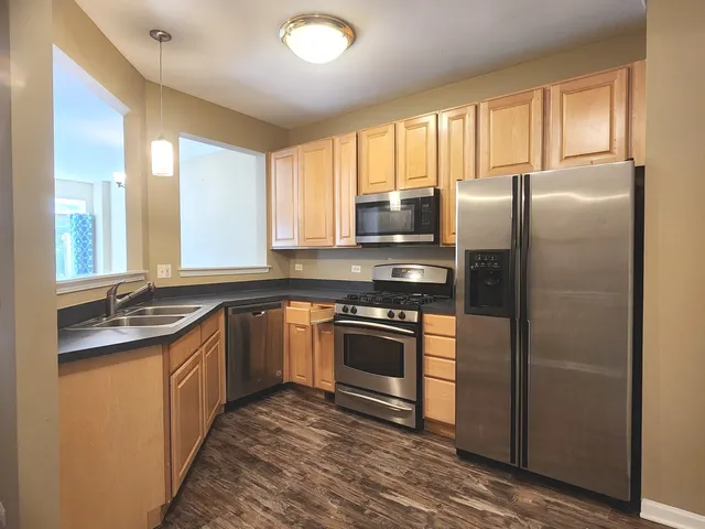 a kitchen with stainless steel appliances granite countertop a refrigerator a sink a stove and cabinets