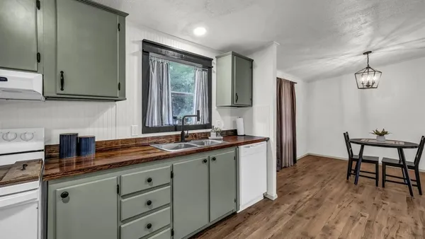 a kitchen with a sink dishwasher a dining table and chairs with wooden floor