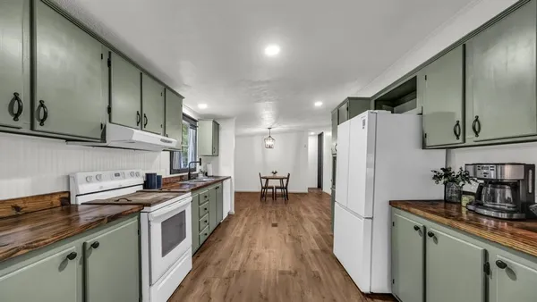 a kitchen with stainless steel appliances a sink dishwasher a refrigerator and a stove with wooden floor