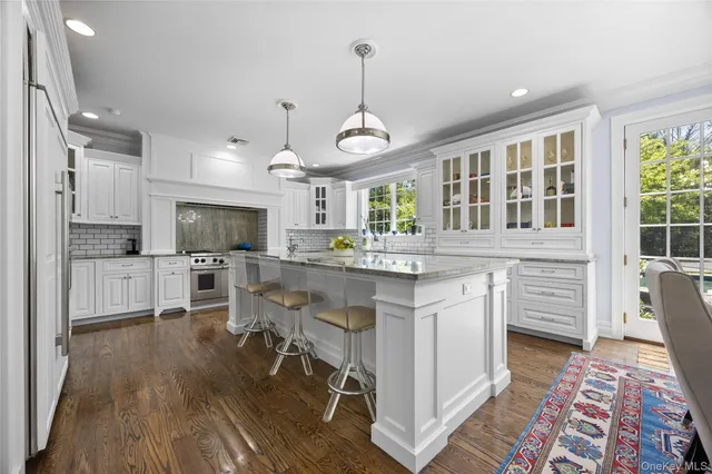 a kitchen with stainless steel appliances kitchen island granite countertop a stove a sink dishwasher a dining table and chairs with wooden floor