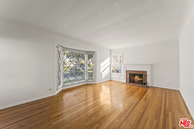 a view of empty room with wooden floor and fireplace