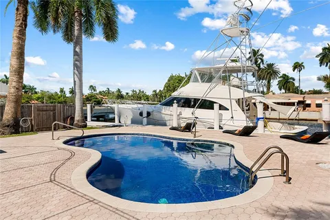 a view of a swimming pool with couches chairs and potted plants