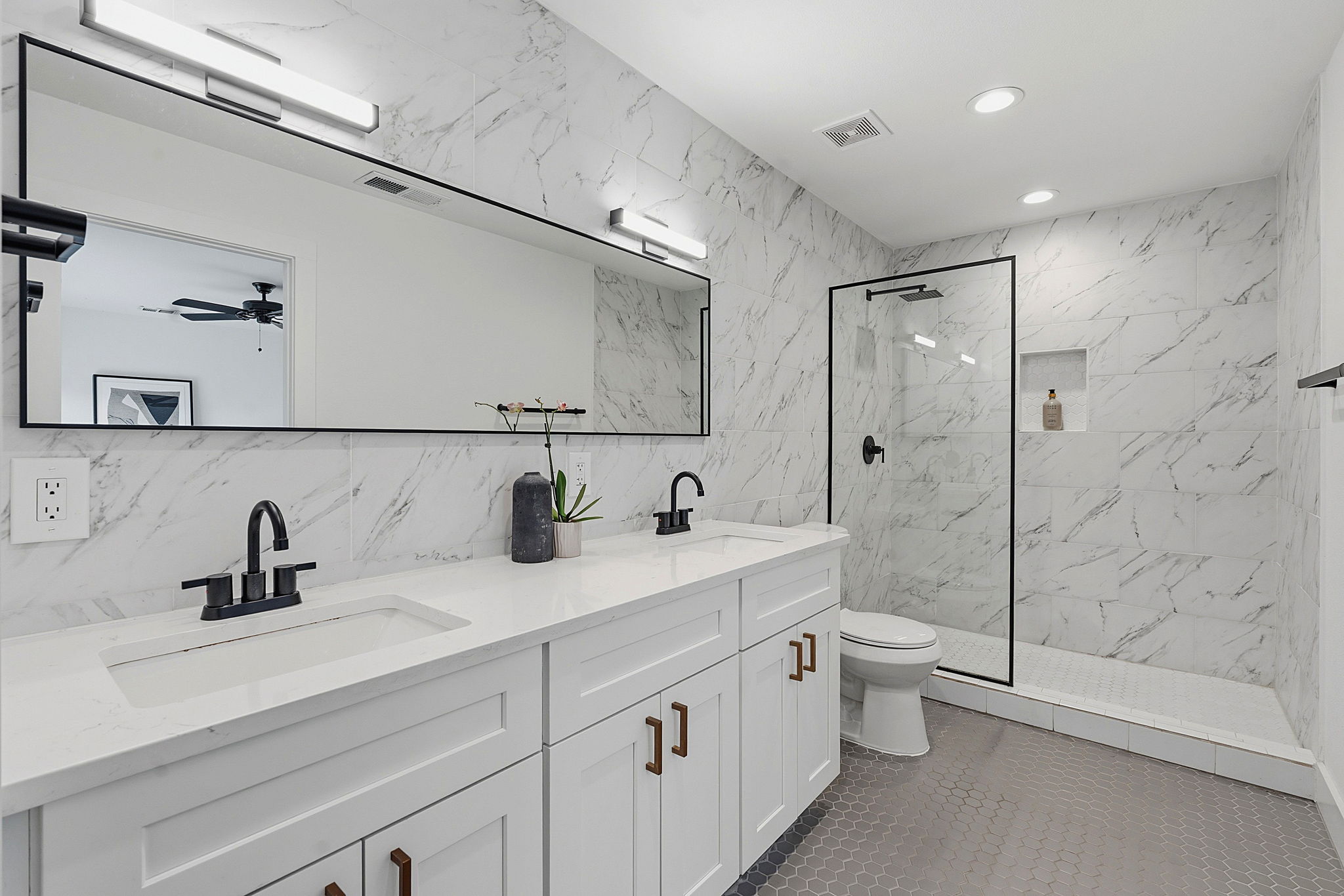 4403 Elmsgrove Drive Austin, TX 78721 - Photo 11 of 38 Dual vanities and a spacious glass-enclosed shower highlight this beautifully tiled primary bathroom.