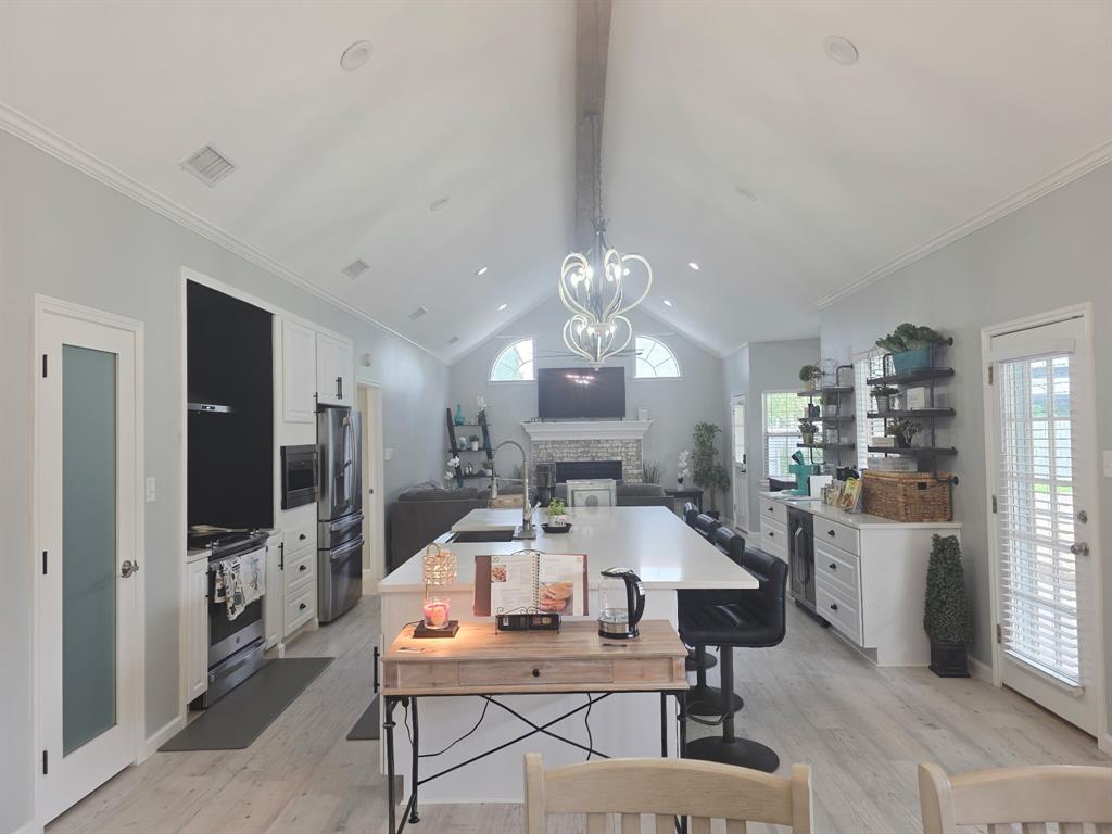 520 Red River Road Belton, TX 76513 - Photo 18 of 36 Open-concept living area with vaulted ceilings and exposed beam, featuring a spacious kitchen island with seating, integrated stainless steel appliances, and wood-finish flooring