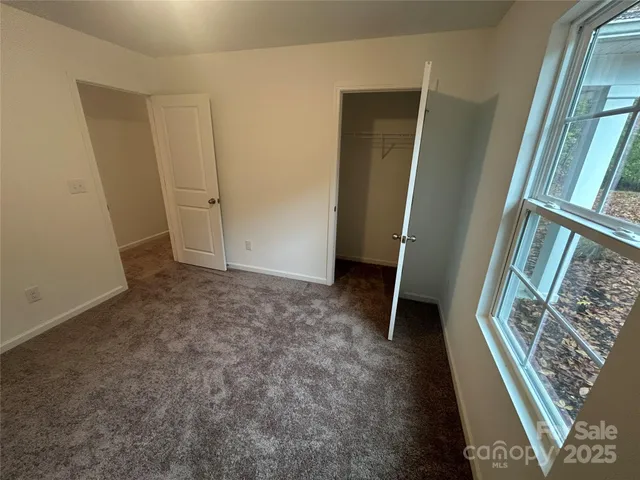 an empty room with walk in closet and wooden floor