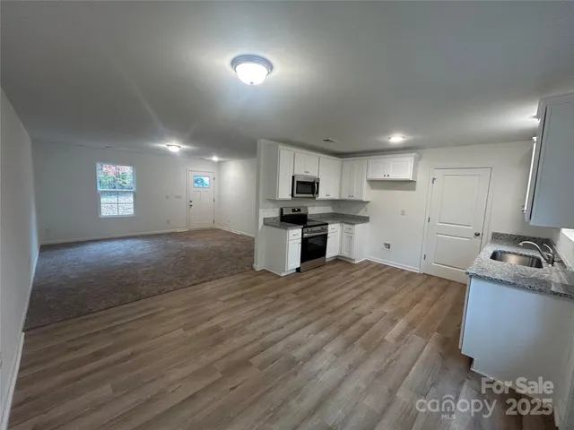 a kitchen with stainless steel appliances granite countertop a stove a sink dishwasher and a refrigerator with wooden floor