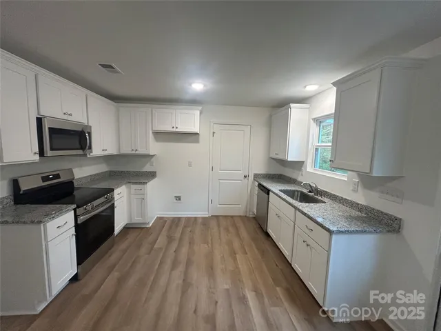 a large kitchen with a stove top oven sink and cabinets