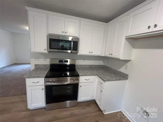 a kitchen with granite countertop white cabinets and stainless steel appliances