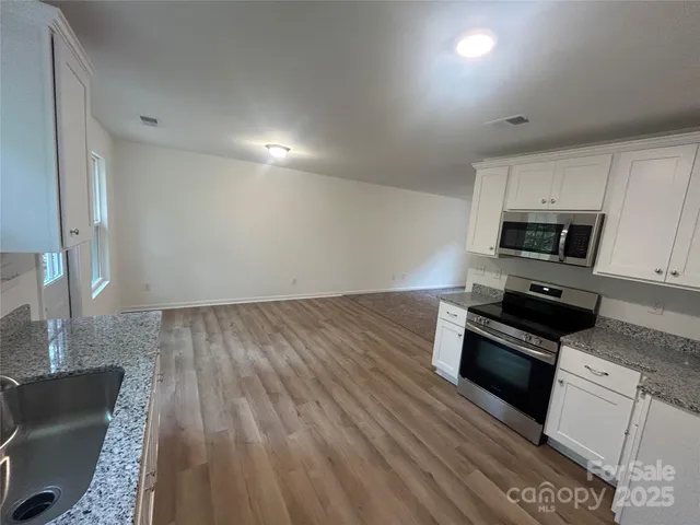 a kitchen with granite countertop a stove microwave and sink