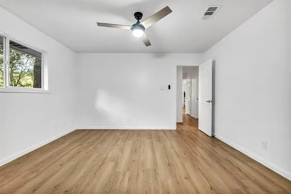 a view of empty room with wooden floor and ceiling fan