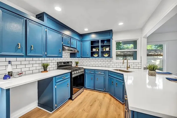 a kitchen with stainless steel appliances granite countertop wooden cabinets a sink dishwasher a stove and a refrigerator with wooden floor