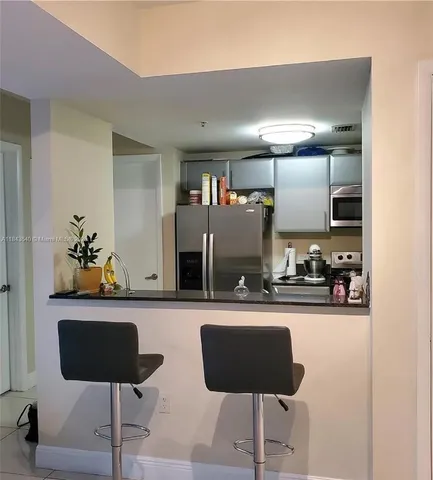 a kitchen with stainless steel appliances kitchen island granite countertop a refrigerator and a stove top oven