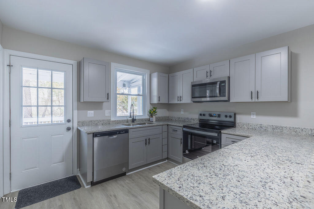 4814 Fayetteville Road Durham, NC 27713 - Photo 10 of 32 a kitchen with kitchen island granite countertop a sink stove and microwave