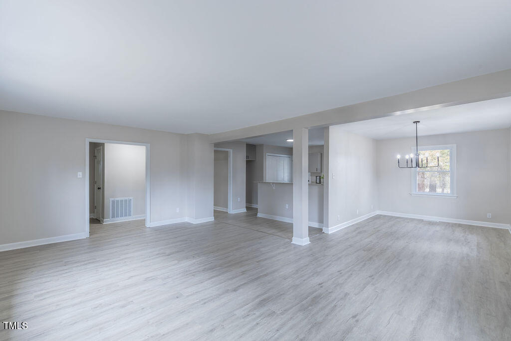 4814 Fayetteville Road Durham, NC 27713 - Photo 5 of 32 an empty room with wooden floor mirror and windows