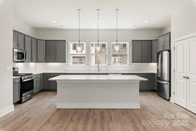 a large kitchen with stainless steel appliances a large counter top a stove a refrigerator and a sink