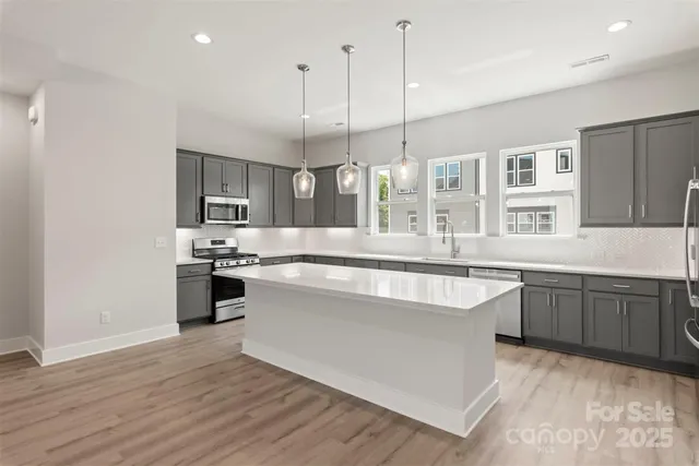 a large kitchen with stainless steel appliances granite countertop a sink a stove and a wooden floors