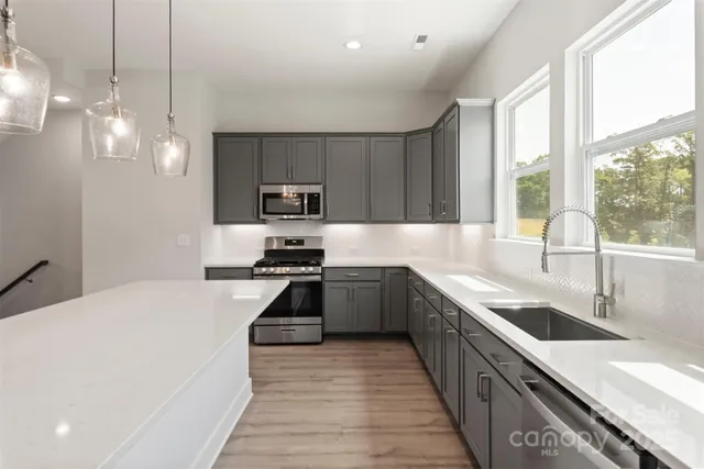 a large kitchen with stainless steel appliances granite countertop a sink a stove and a refrigerator