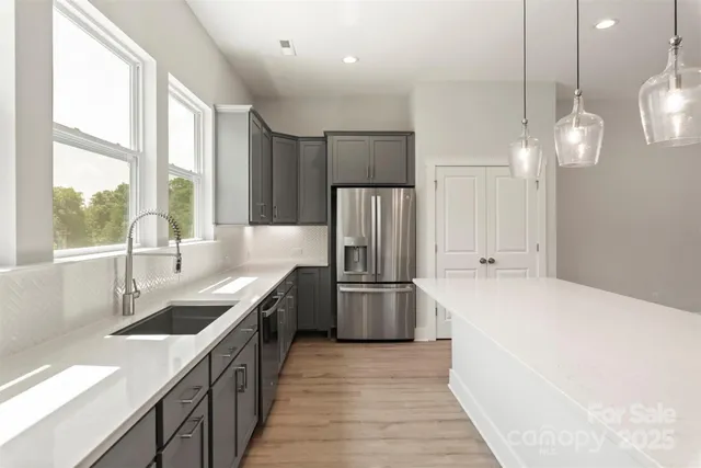 a kitchen with a sink a counter top space stainless steel appliances cabinets and a large window