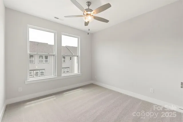 an empty room with windows and fan