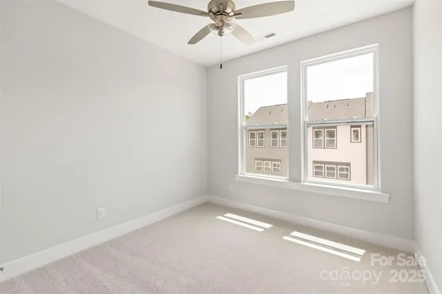 an empty room with windows and ceiling fan