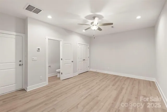 an empty room with wooden floor and ceiling fan