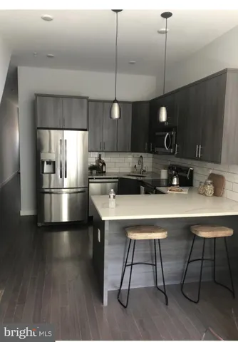 a kitchen with stainless steel appliances a table chairs refrigerator and microwave