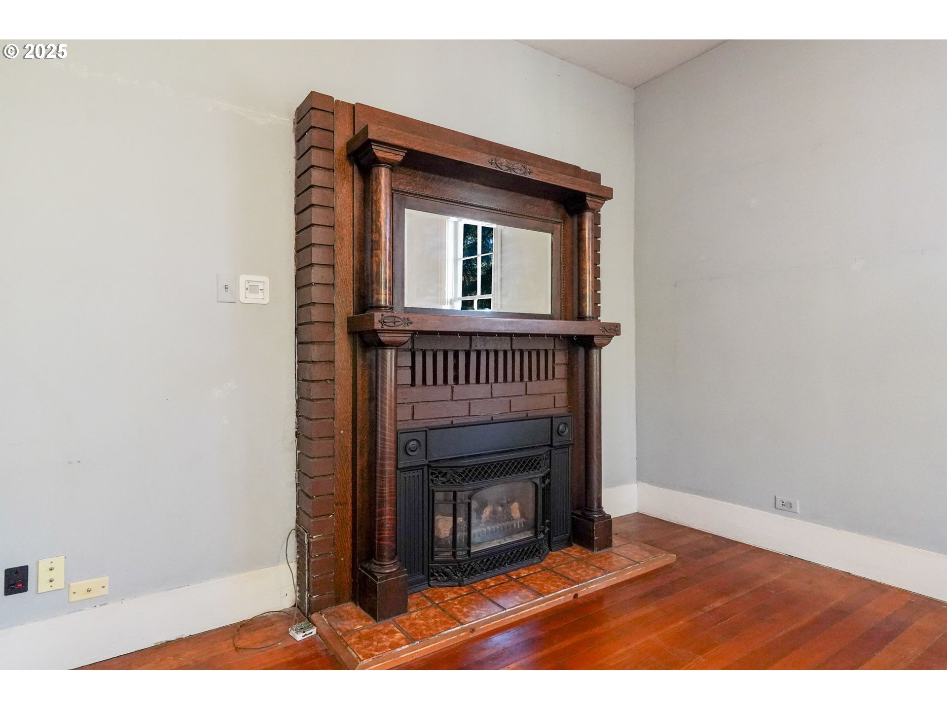 10478 Crosby Road Northeast Woodburn, OR 97071 - Photo 7 of 43 a view of an empty room with wooden floor fireplace and a window