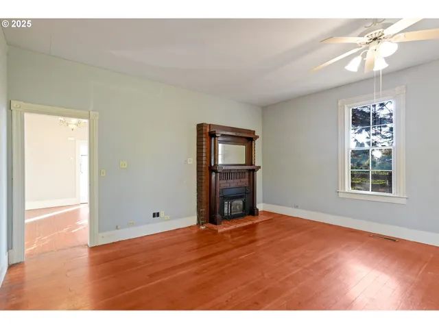 a view of an empty room with window and wooden floor