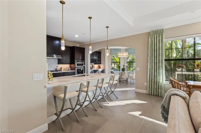a kitchen with stainless steel appliances kitchen island granite countertop a dining table chairs and white cabinets