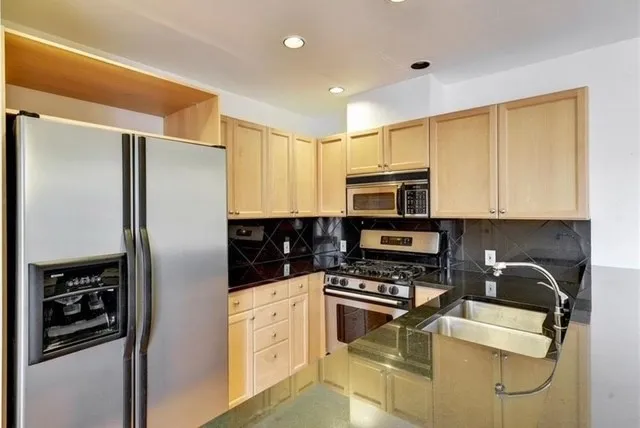 a kitchen with stainless steel appliances granite countertop a refrigerator and a stove top oven