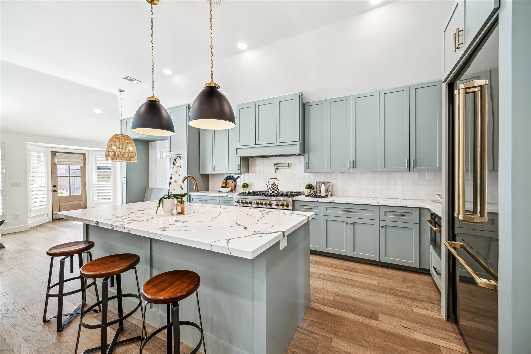 a kitchen with kitchen island granite countertop a sink a stove and chairs