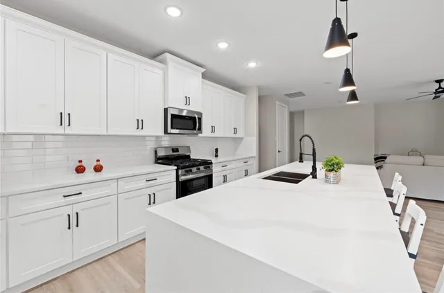 a kitchen with granite countertop white cabinets and appliances