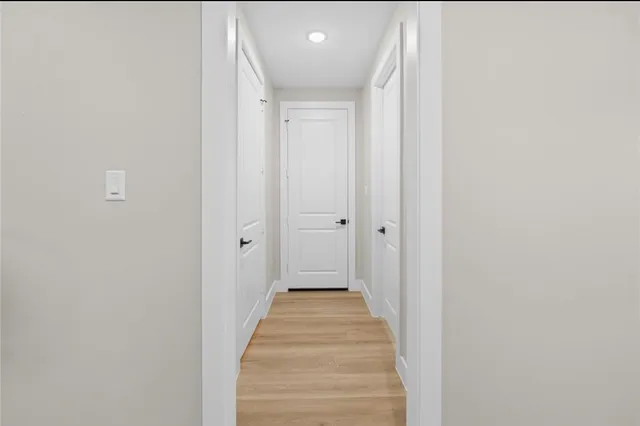 a view of a hallway with wooden floor and a bathroom