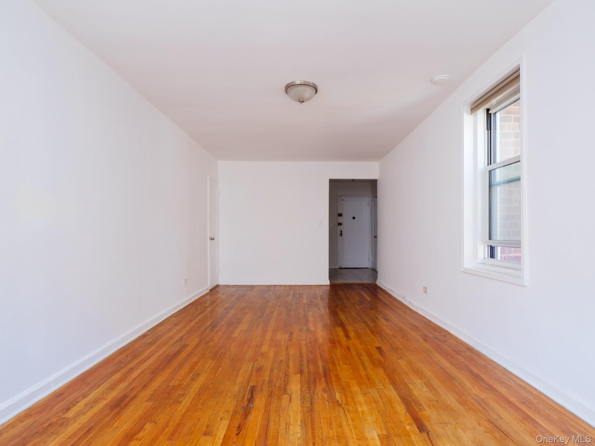 34-15 74th Street, Unit 4H Queens, NY 11372 - Photo 8 of 19 a view of an empty room with wooden floor and a window