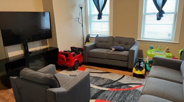 a living room with furniture a flat screen tv and a window