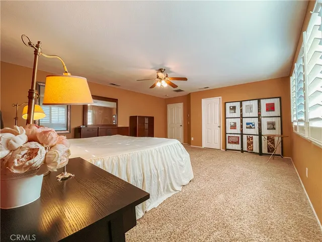 a spacious bedroom with a bed a dresser and a chandelier