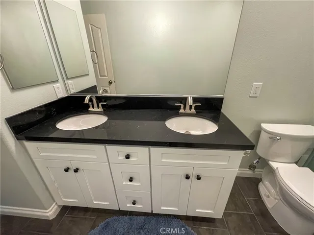 a bathroom with a granite countertop double vanity sink and a mirror