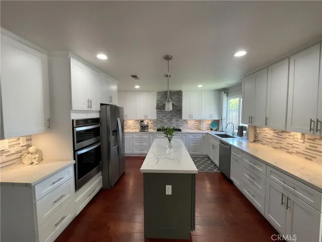a large kitchen with kitchen island a sink a counter space stainless steel appliances and cabinets
