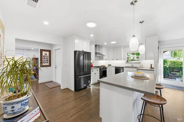 a large white kitchen with stainless steel appliances kitchen island granite countertop a refrigerator and a stove top oven