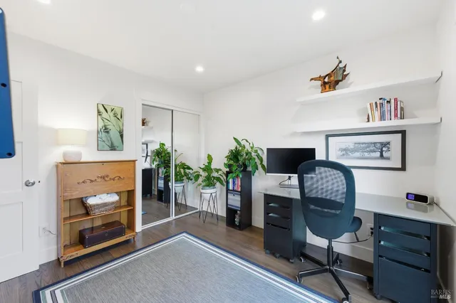 a view of a hallway with wooden floor and a bathroom