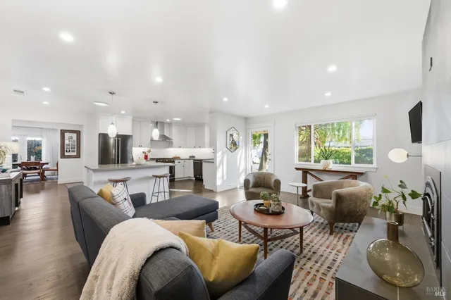 a kitchen with stainless steel appliances kitchen island granite countertop a table chairs refrigerator and microwave